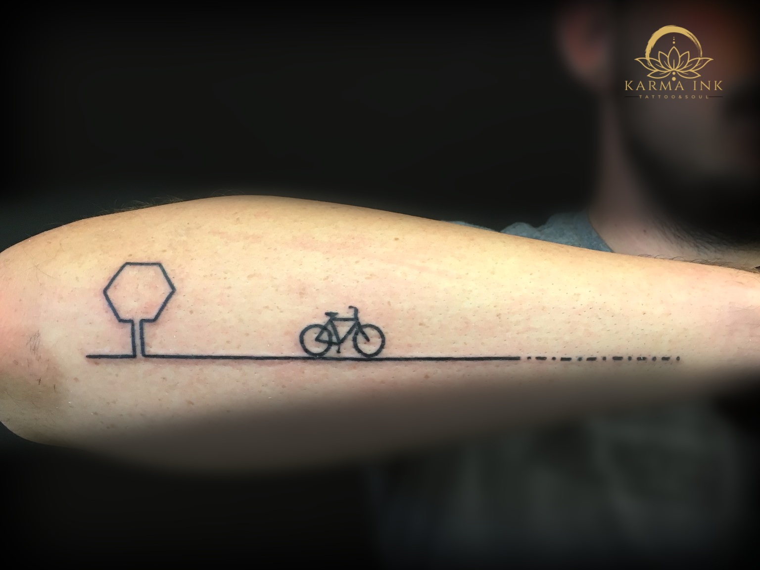 Reduziertes Fahrrad-Tattoo als feine Linie am Oberarm
