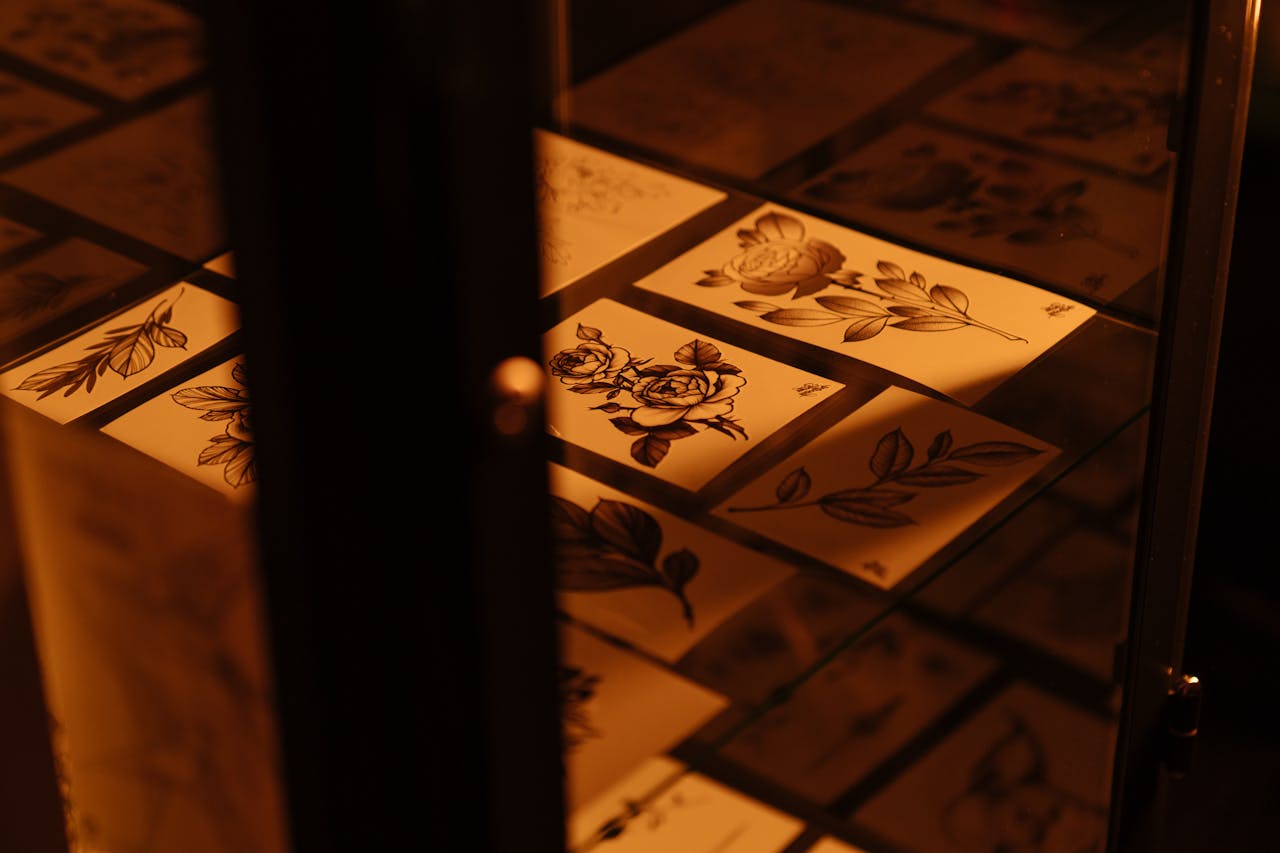 menu-03 Intricate floral tattoo sketches displayed in a tattoo studio under warm lighting.