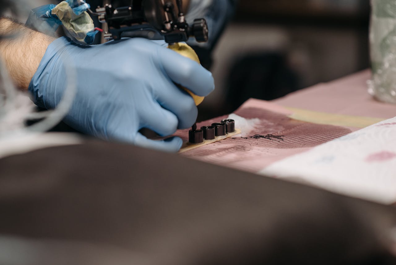 Tattoo artist with gloves setting up ink for tattooing in a studio.